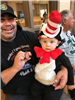 A man holding a small child dressed as the Cat in the Hat