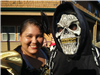 A woman posing with a person wearing a skull mask