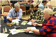 Three people looking at leaves and writing in notebooks