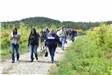 A group of people waling down a trail from where vehicles are parked