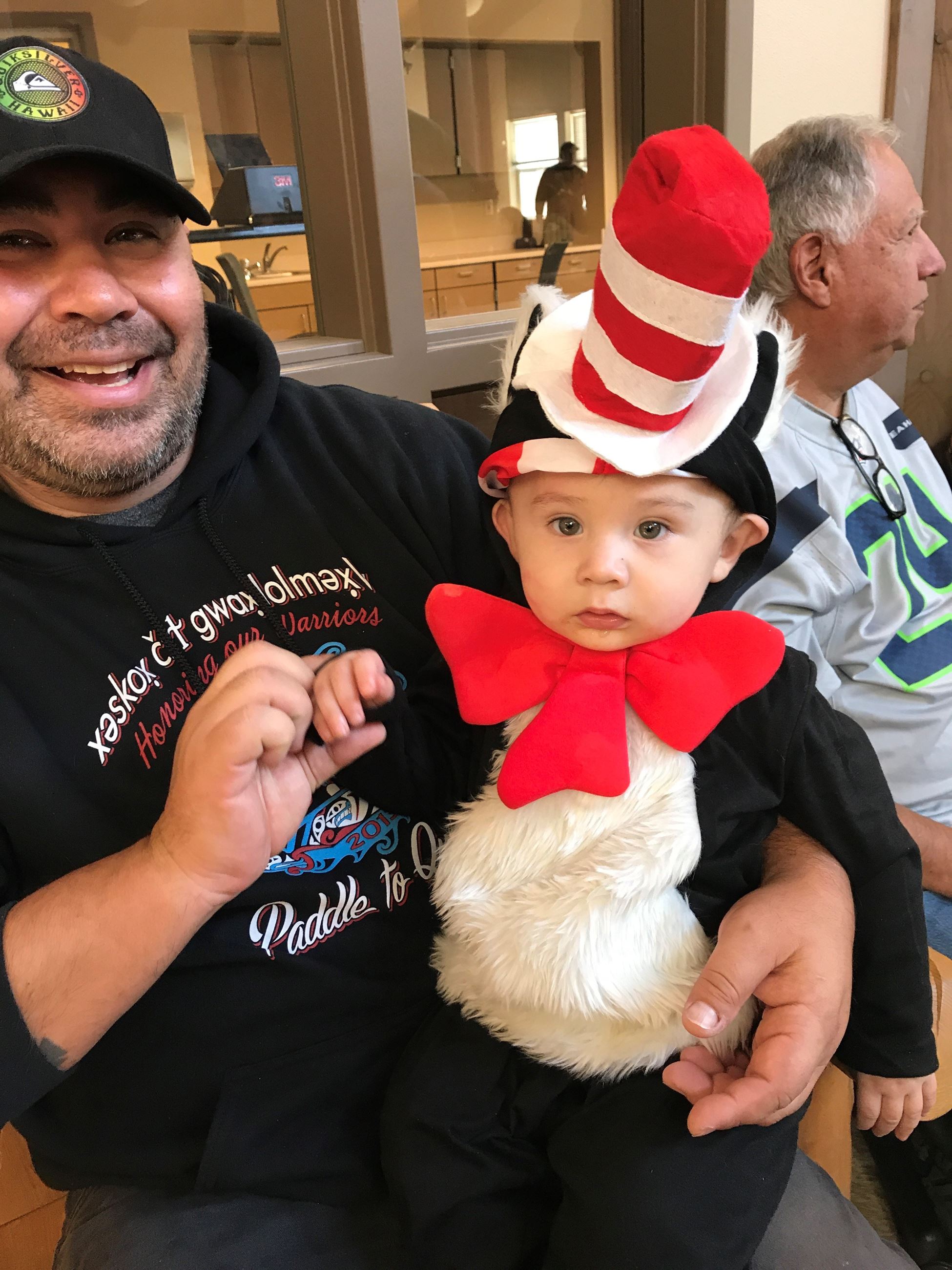 A man holding a small child dressed as the Cat in the Hat