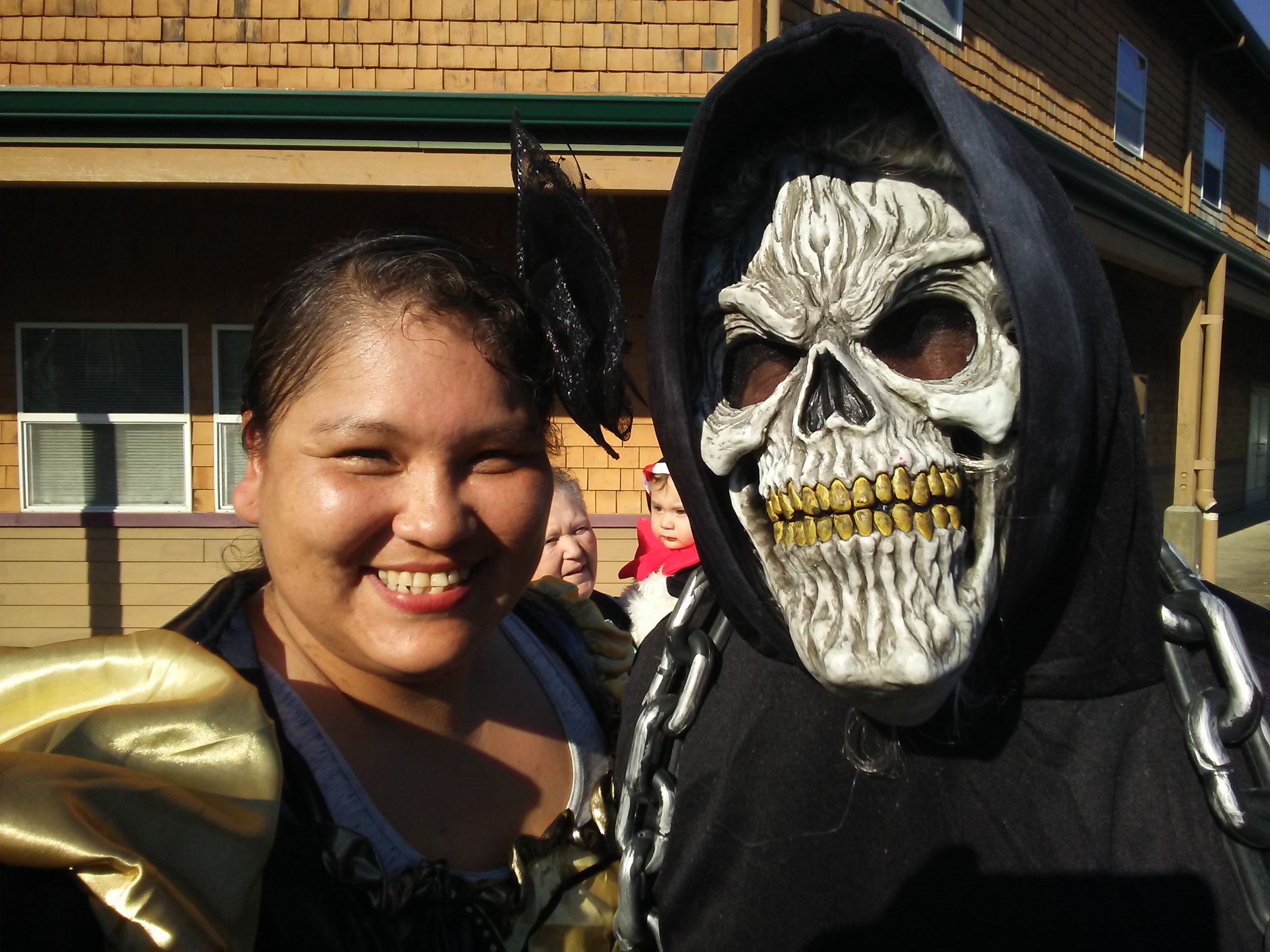 A woman posing with a person wearing a skull mask