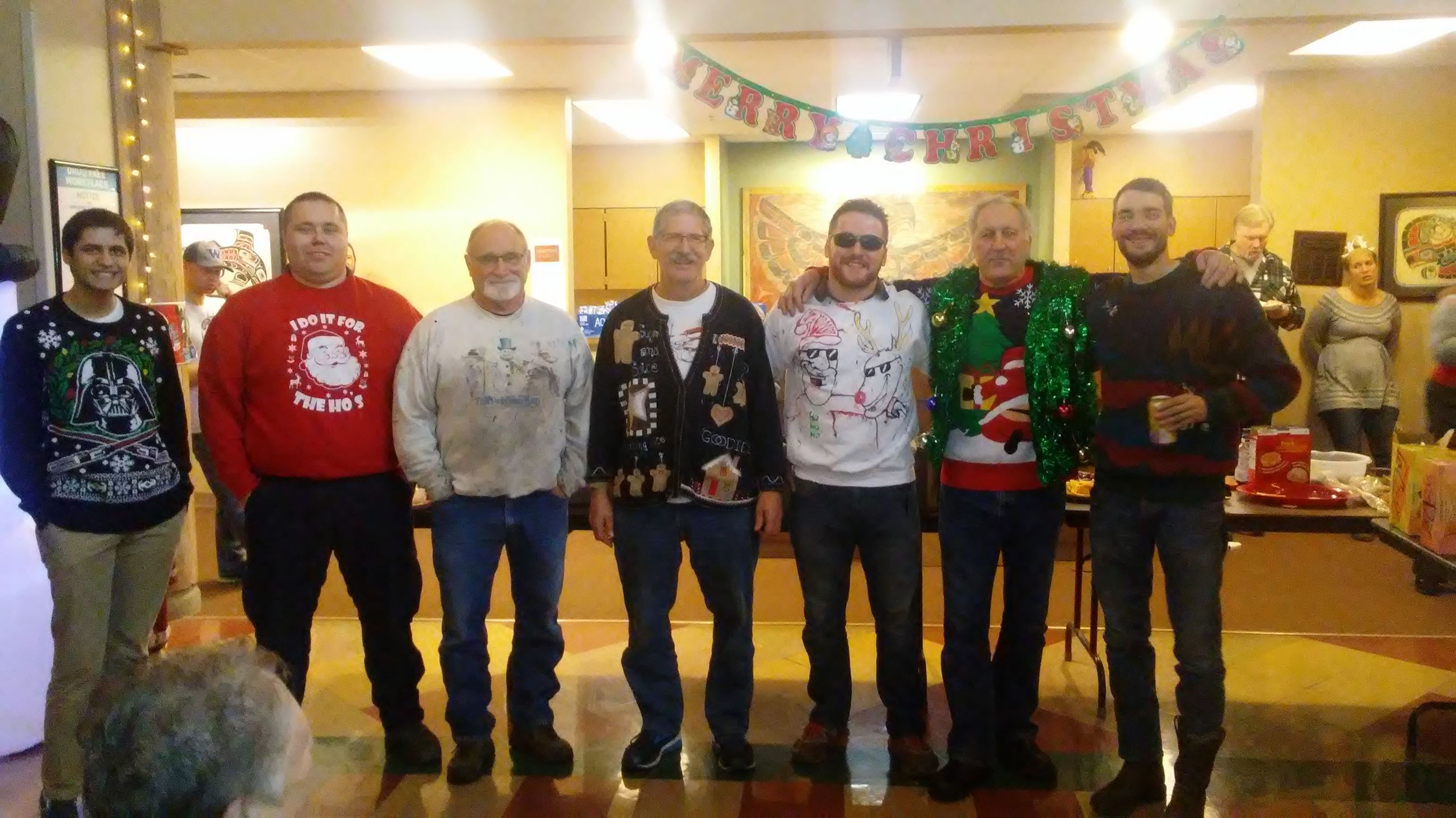 A line of men wearing ugly holiday sweaters