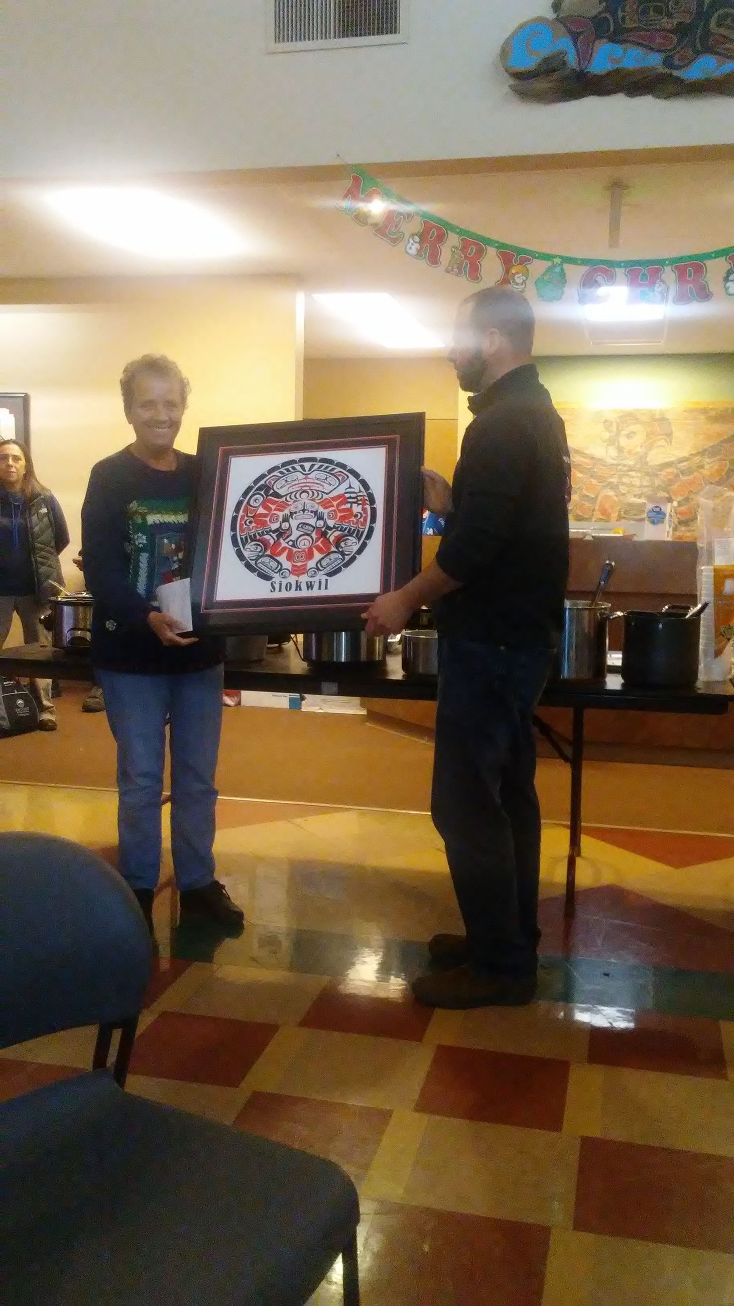 Two people holding one framed picture