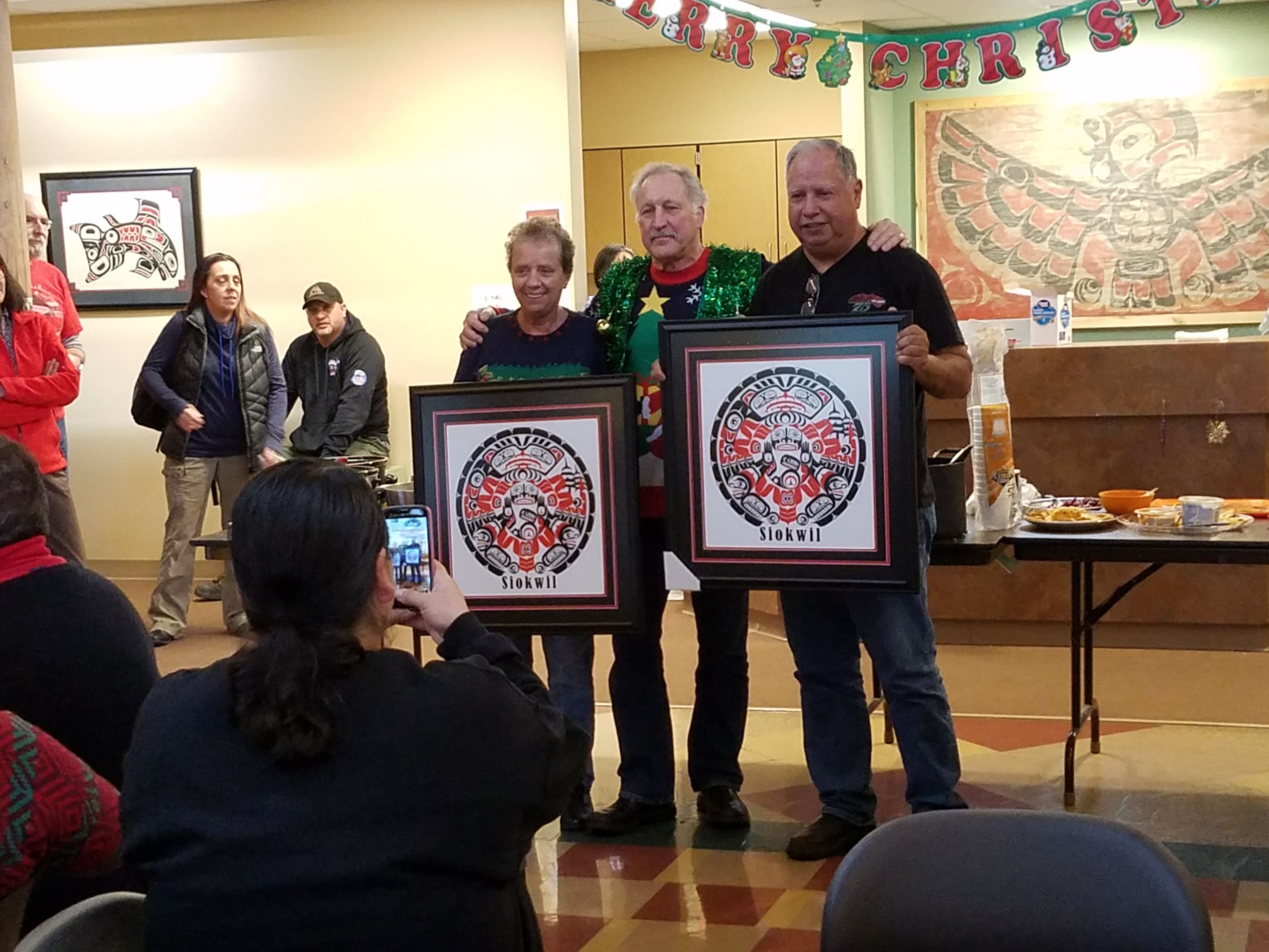 Two people holding framed pictures