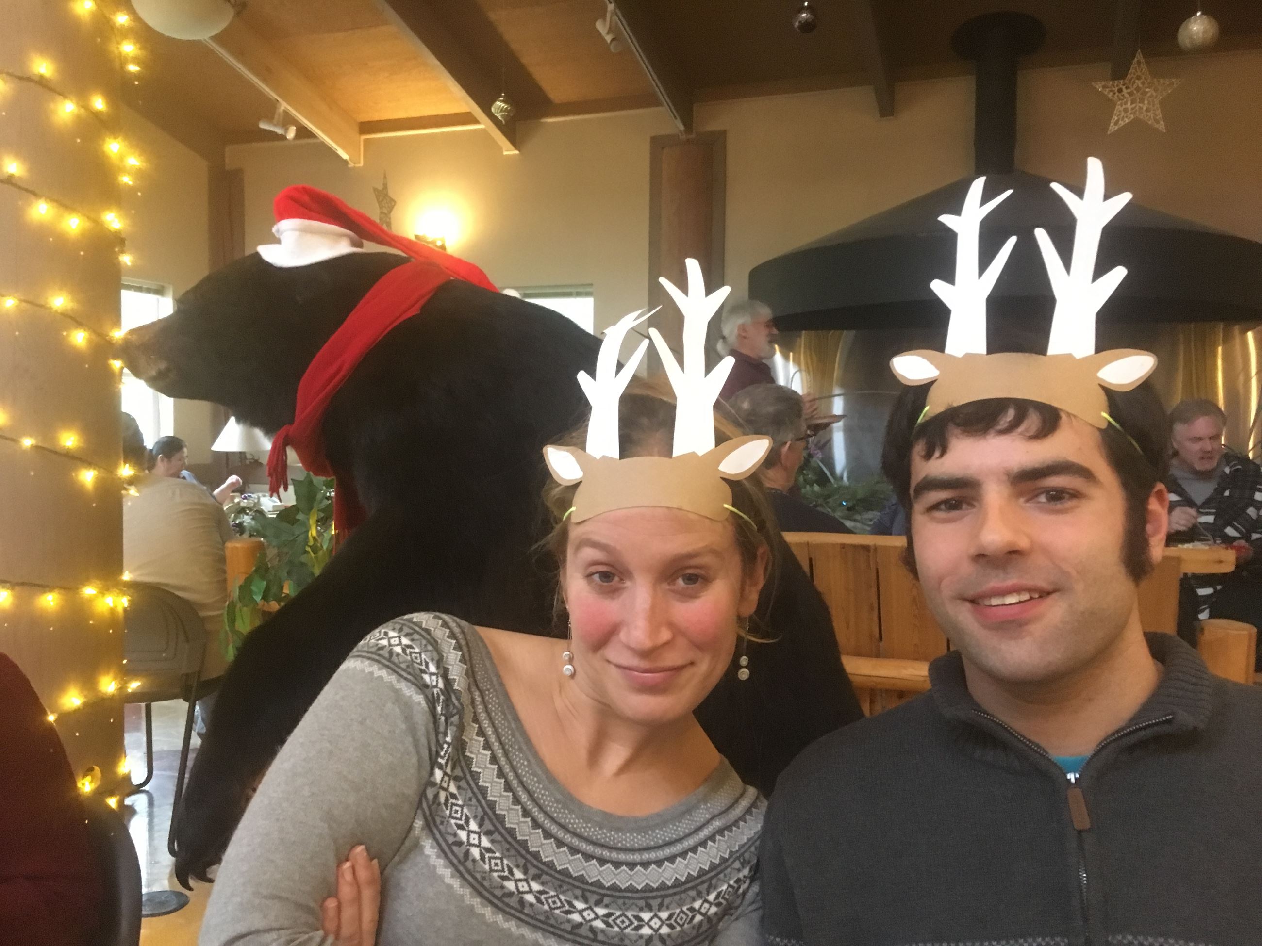 Two people wearing paper reindeer antlers
