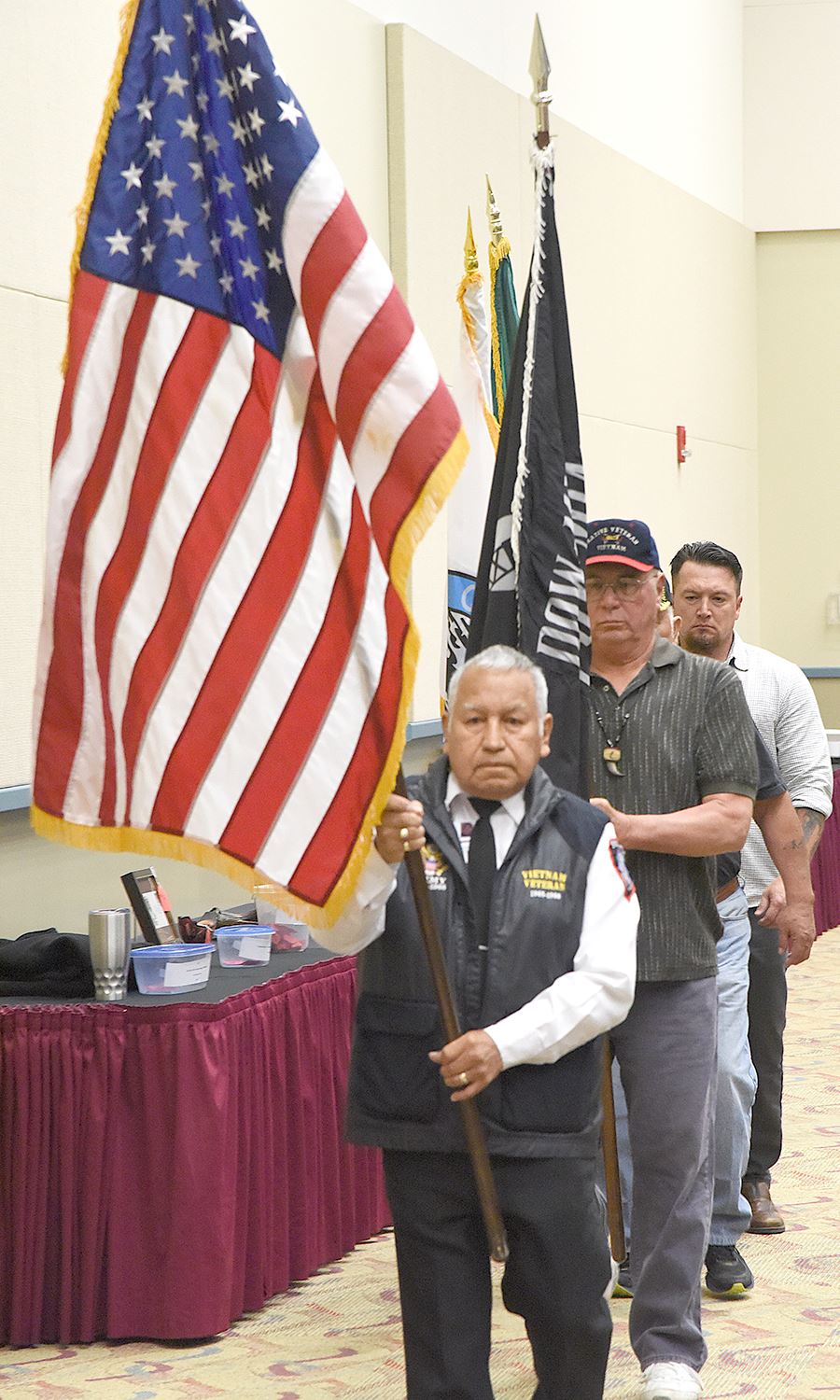 Three men line up carrying an American flag and a tribal flag