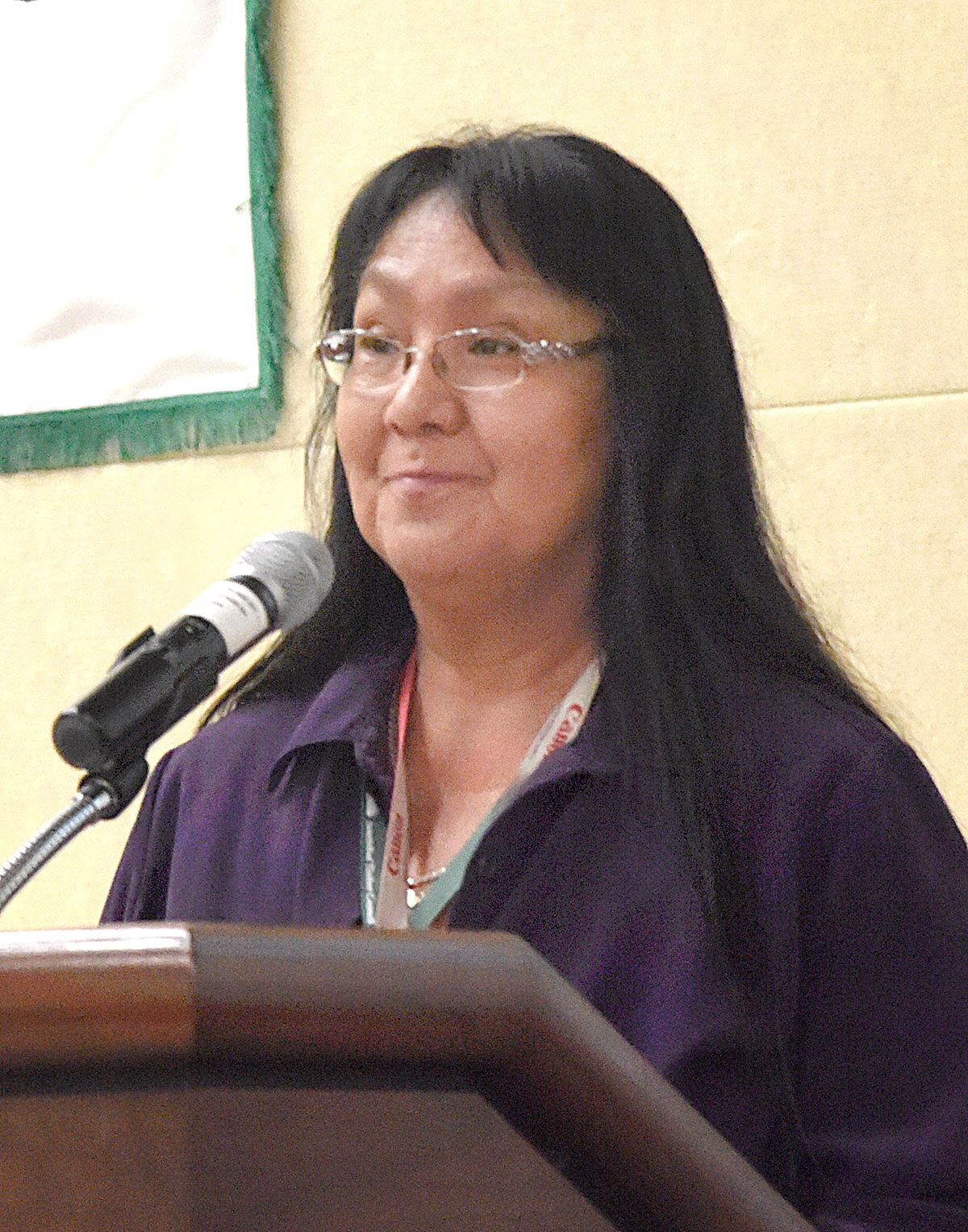 A woman at a podium speaks into a microphone