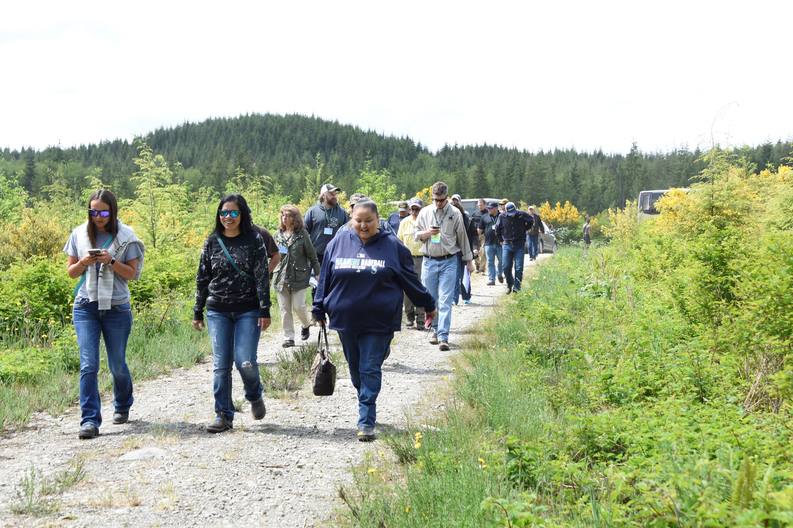 A group of people waling down a trail from where vehicles are parked