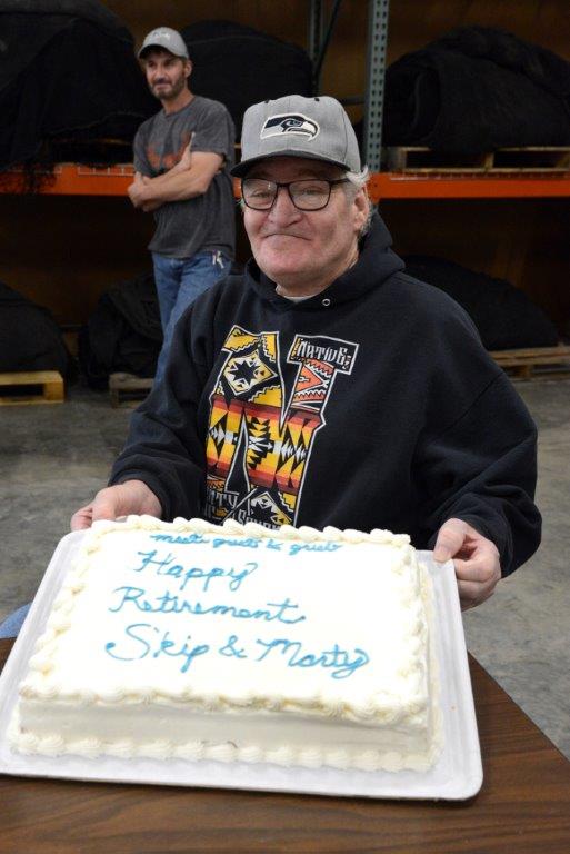 Man holding a cake that says Happy Retirement Skip  and Marty