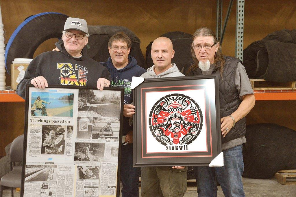 Men holding framed news stories and a picture