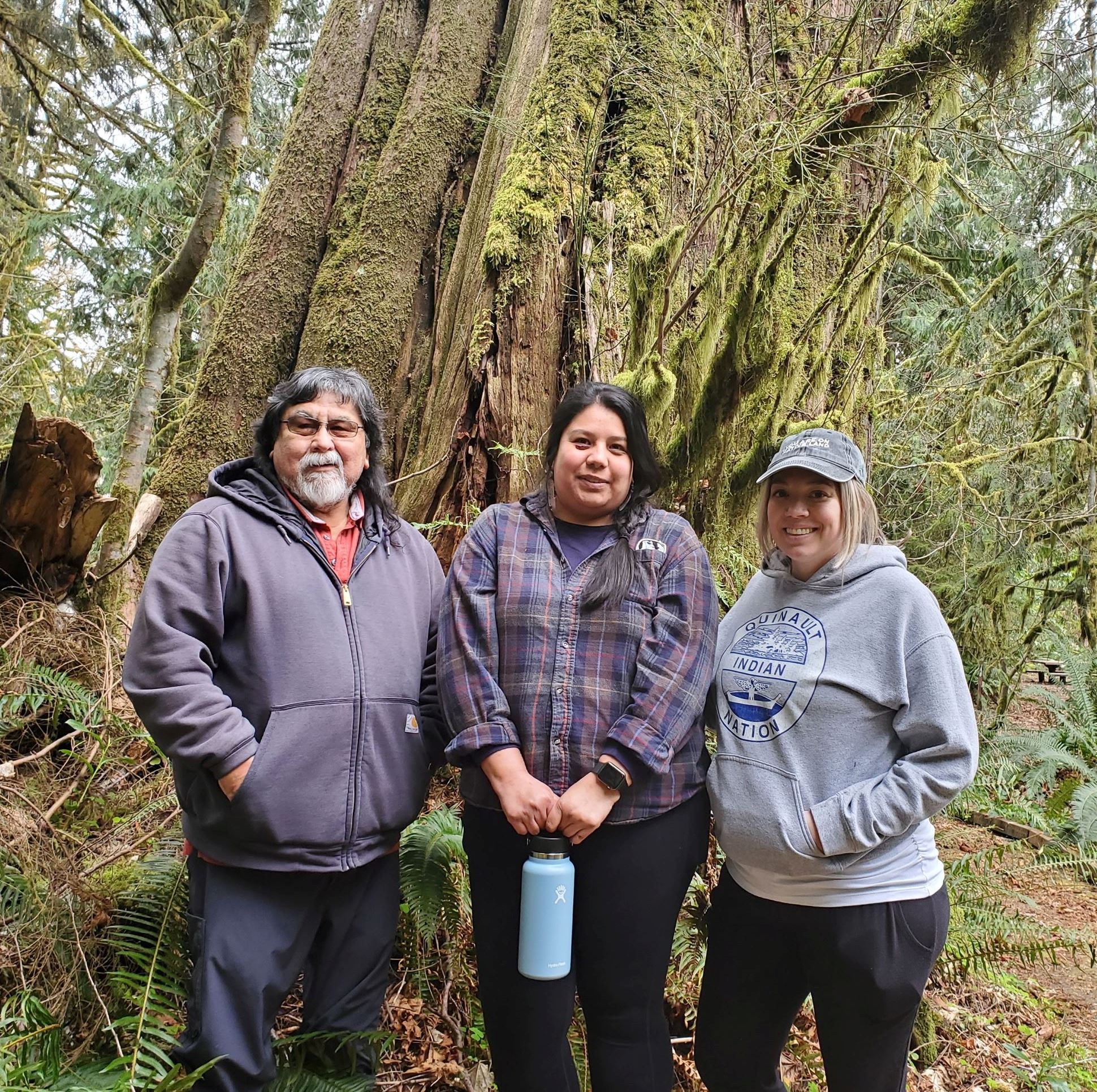 group of people standing in front of a large tree