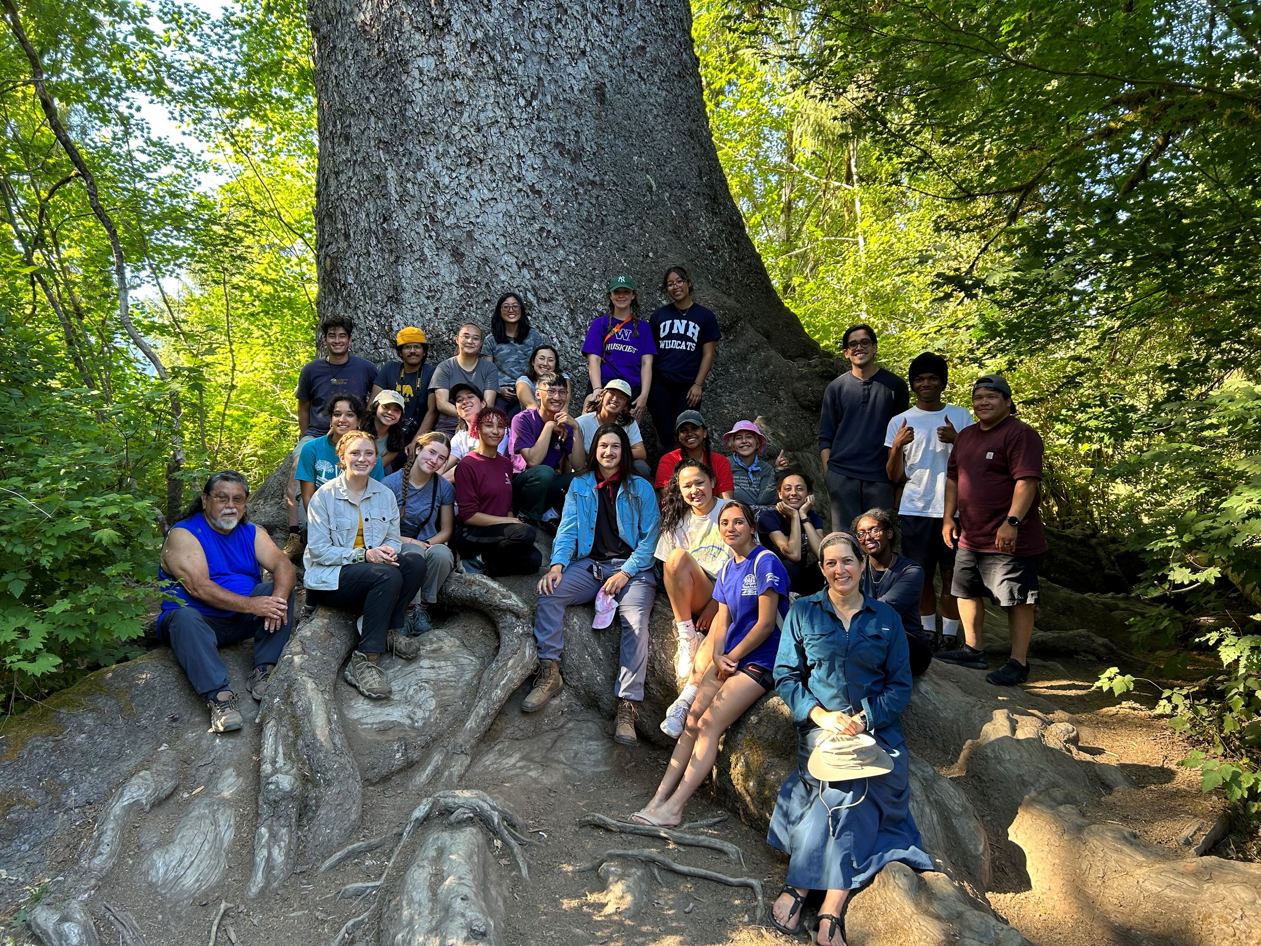 group of students posing in front of largest spruce tree