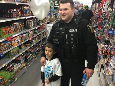 Police man standing with a child holding a balloon